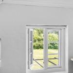 Ein Raum mit weiß gestrichenen Wänden und einem offenen Fenster zum Garten.