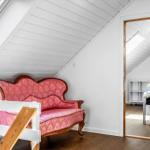 Ein Raum mit einem rosa Sofa und einem Schlafzimmer im Hintergrund.