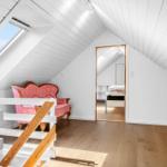 Schlafzimmer mit Dachschrägen, Holzboden und rosa Sofa