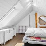 Schlafzimmer mit Dachschräge, Fenster, Bett und Schränken.