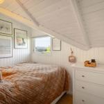 Schlafzimmer mit Bett, Schrank und Fenster unter Dachschrägen.