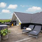 Terrasse mit Liegen, Grill und Tisch unter blauem Himmel.