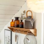 Holzregal mit Glasflaschen und Kanne an weißer Wand