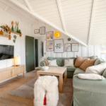Wohnzimmer mit Sofa, Fernseher und Holzmöbeln unter schrägem Dach.