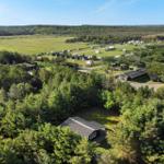 Liegenschaft mit Wald, Grünflächen und Campingplätzen unter blauem Himmel.