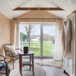 Raum mit Holzwand, Sitzgelegenheit und Glasfront zum Garten