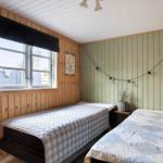 Zwei Betten mit Quilt in einem Raum mit Holzwänden und Fenster.