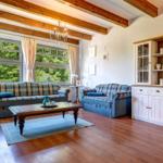 Living room with wooden beams, two sofas, and glass cabinet