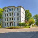 White villa with multiple windows and green surroundings