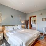Bedroom with double bed, nightstands, and chair. Wooden floor and wall decor.