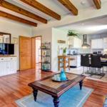 Living and kitchen area with wooden floor and massive beams.