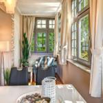 Essbereich mit Tisch, Stühlen und Fenstern mit Vorhängen.