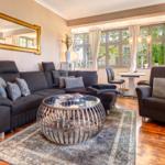 Wohnzimmer mit Sofa, Sessel und Glas-Tisch vor Fenster