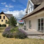 Haus mit Dachterrasse, Garten und Lavendel. Roter Sonnenschutz und Gartenmöbel.