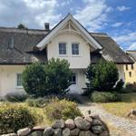 Haus mit strohgedecktem Dach und gepflasterter Zugangsweg.