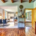 Wohnbereich mit Essbereich und Küche. Holzdielen und ein Schlafzimmer sind sichtbar.