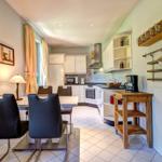 Küche mit Essbereich, weiße Schränke, Esstisch mit Stühlen und Küchenzeile.