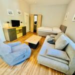 Wohnzimmer mit Sofa, Sessel, Bett und Fernseher.