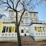 Ein zweistöckiges Haus mit Glasveranda und Stufen zur Eingangstür.