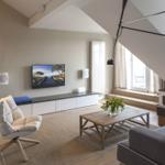 Wohnzimmer mit TV, Sofa, Sessel und Holztisch unter Dachschrägen.