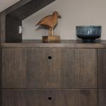 Schrank mit Holzoberfläche, darauf Holzvogel und blaue Schale.