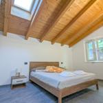 Schlafzimmer mit Holzdecke, Bett und Fenster