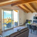 Wohn- und Essbereich mit Blick auf See und Berge. Terrasse mit Sitzmöbeln.