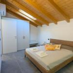 Schlafzimmer mit Holzdecke, Bett, Kleiderschrank und Bodenfliesen.