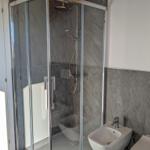 Dusche mit Glaswand, Bidet und Toilette in moderner Badezimmerausstattung.