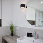 Badezimmer mit Waschbecken, Spiegel und Dusche.