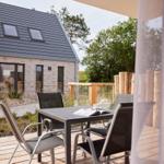 Terrasse mit Tisch und Stühlen, Blick auf modernes Haus mit Dachfenstern.