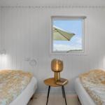 Zwei Betten mit gemusterten Bettdecken, ein Nachttisch mit Lampe und Blick auf eine Terrasse.