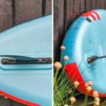 Blauer Stand-Up-Paddleboard mit rotem Rand lehnt an eine Holzwand.