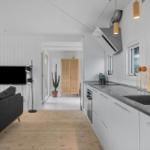 Küche und Wohnbereich mit Sofa, Fernseher und Holzboden.