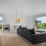 Wohnbereich mit Sofa, Esstisch und Küchenzeile. Große Fenster bieten Blick auf die Umgebung.