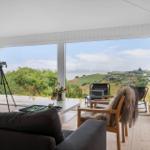 Wohnzimmer mit Blick auf Landschaft und See. Es gibt einen Sofa, einen Stuhl und ein Fernrohr.