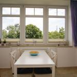 Essbereich mit weißem Tisch, Stühlen und Blick auf Bäume.