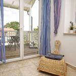 Terrassentür mit blauen Vorhängen führt auf eine Holterrasse mit Tisch und Stühlen.