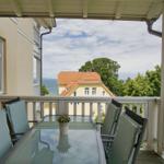 Terrasse mit Tisch und Stühlen. Blick auf Haus und Meer.