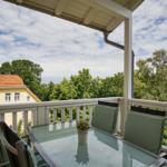 Terrasse mit Tisch und Stühlen, Blick auf Haus und Bäume