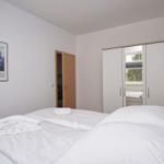 Schlafzimmer mit Doppelbett, Kleiderschrank und Bild an der Wand.