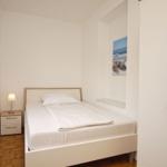 Schlafzimmer mit Bett, Nachttisch und Kleiderschrank.