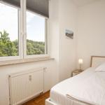 Schlafzimmer mit Bett, Nachttisch und Fenster zum Wald.