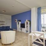 Wohn- und Essbereich mit blauer Wand, Sofa und Blick auf Balkon.