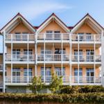 Drei-Stöckiges Haus mit weißen Balkonen und rotem Dachziegel