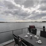 Terrasse mit Tisch, Stühlen und Grill am Wasser