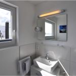 Badezimmer mit Waschbecken, Spiegel und Fenster zur Aussicht.