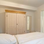 Schlafzimmer mit Bett, Kleiderschrank und Spiegel.