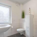 Badezimmer mit Waschbecken, Toilette und Dusche. Fenster mit Mosaikglas.