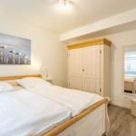 Schlafzimmer mit Bett, Kleiderschrank und Wandbild mit Möwen.